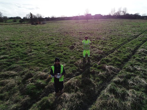 Two people in high viz PPE standing in field with thumbs up